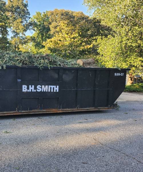 A black dumpster sitting on top of a gravel road